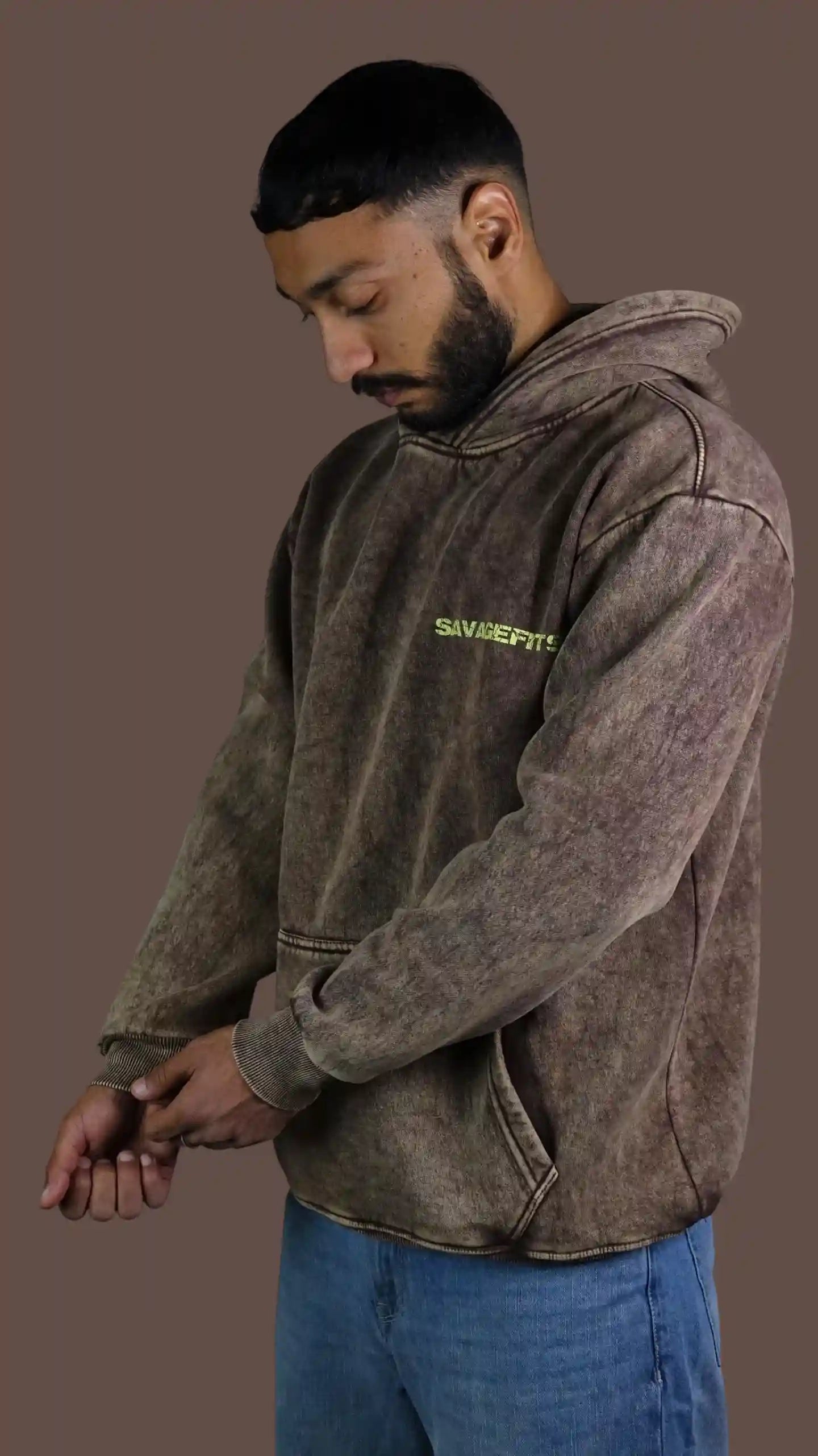 Man wearing a brown Acid wash hoodie with visible branding on a brown background