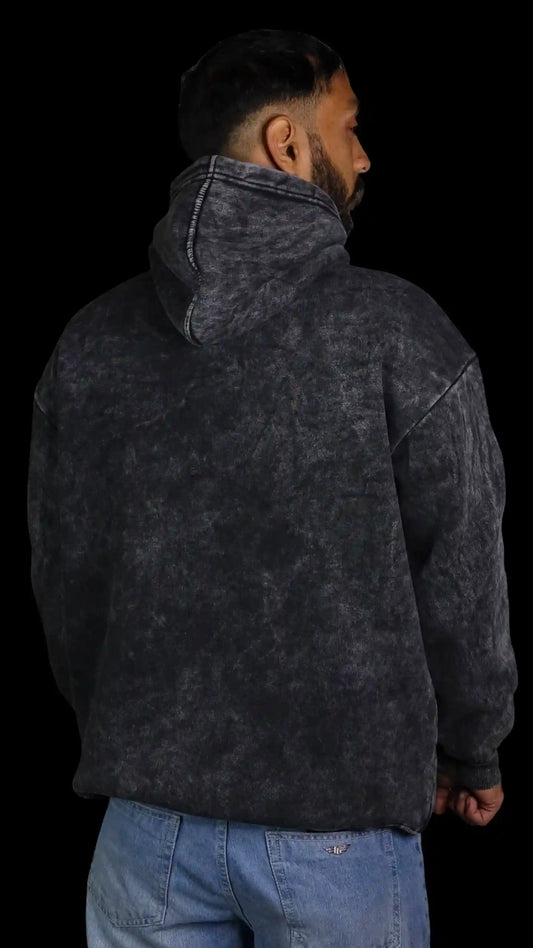 Person wearing a dark gray Acid wash hoodie with a black background