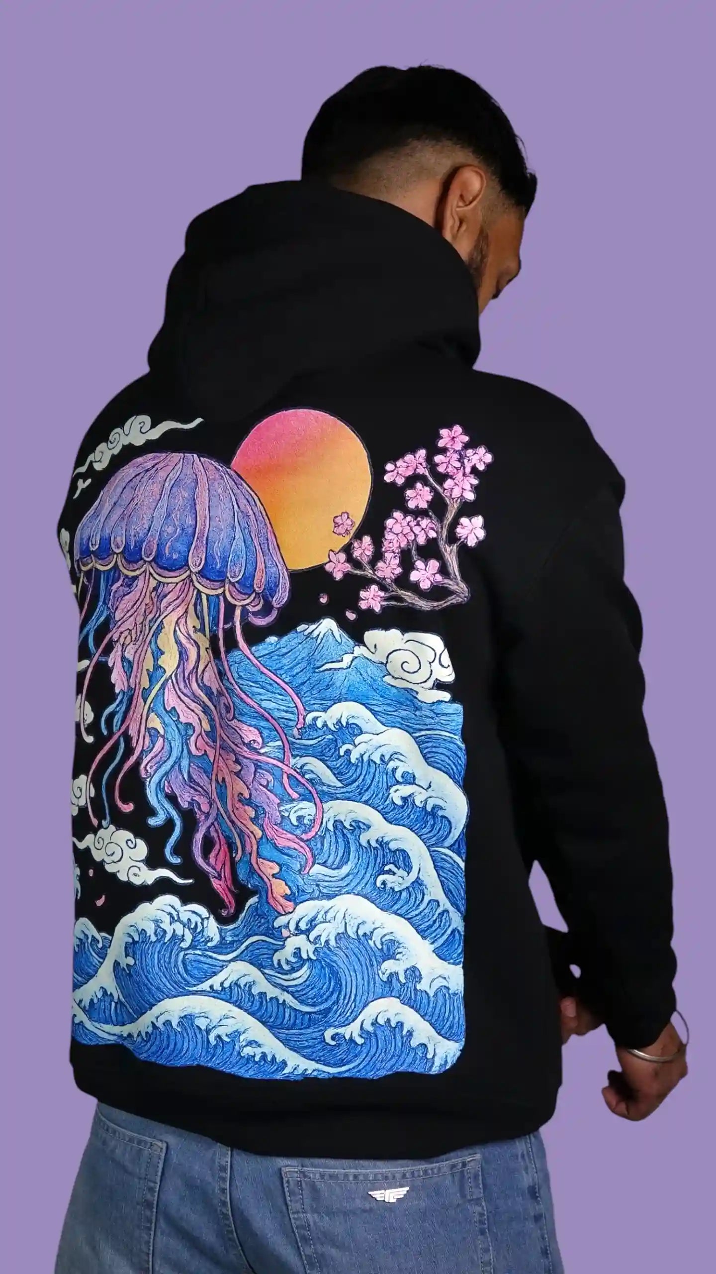 Person wearing a black hoodie with a colorful jellyfish design on the back against a purple background
