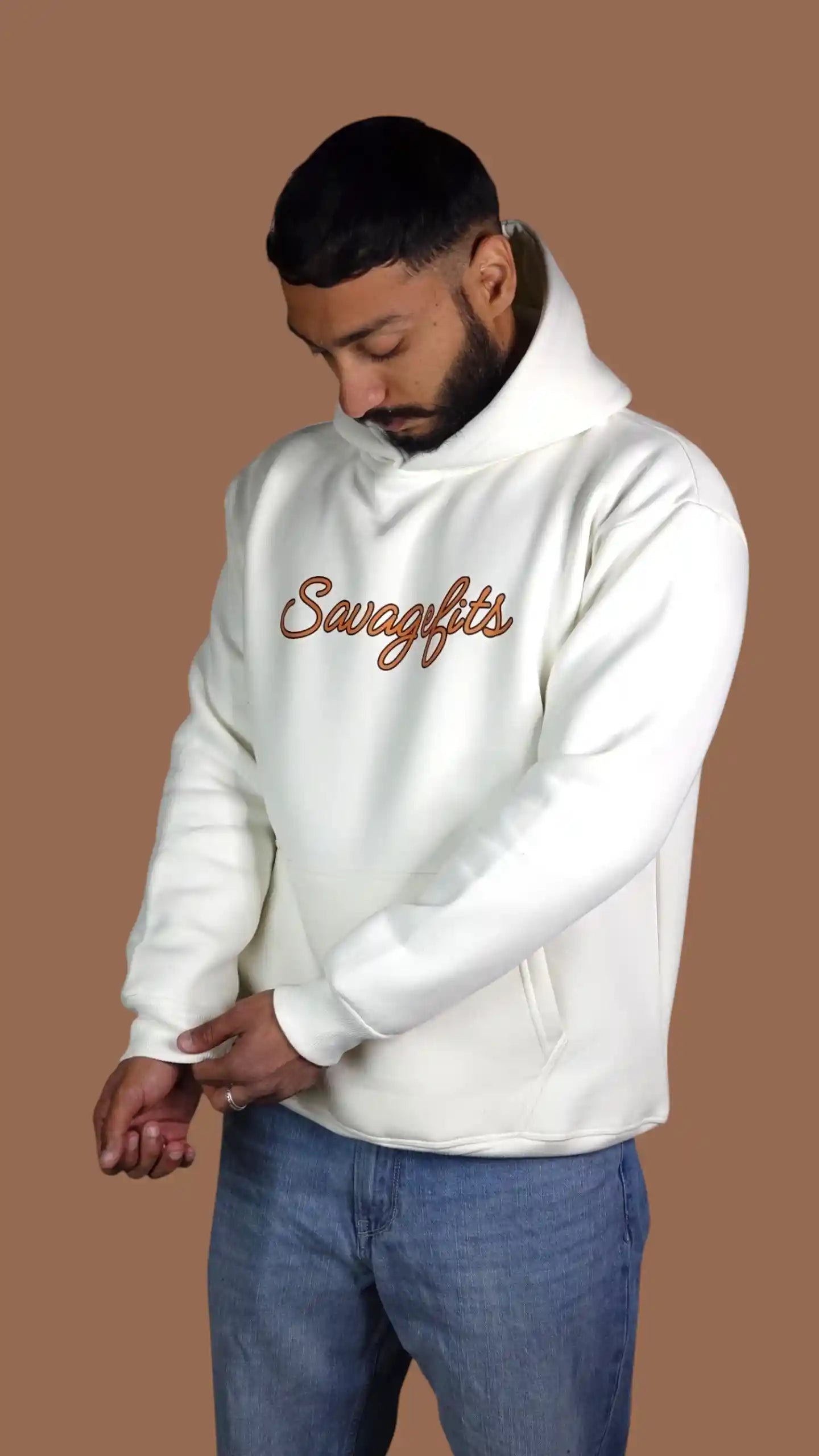Man wearing a white hoodie with 'Savagefits' logo on a brown background